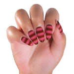 A close-up of a hand with long almond-shaped nails decorated in alternating horizontal stripes of dark brown and vibrant pink.