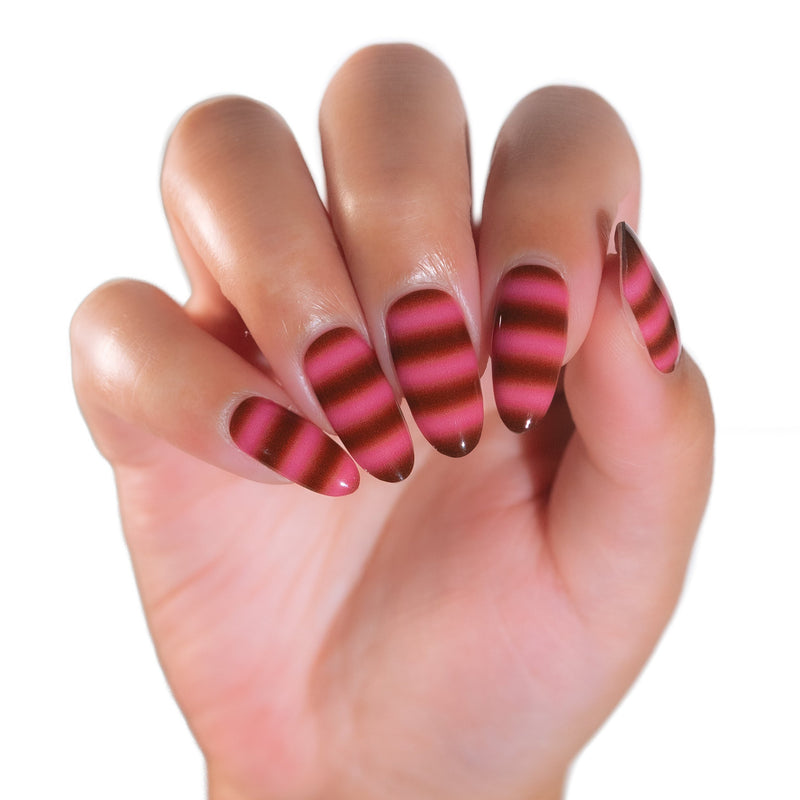 A close-up of a hand with long almond-shaped nails decorated in alternating horizontal stripes of dark brown and vibrant pink.