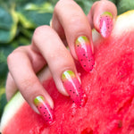 Hand with watermelon-themed nail art holding a slice of watermelon.