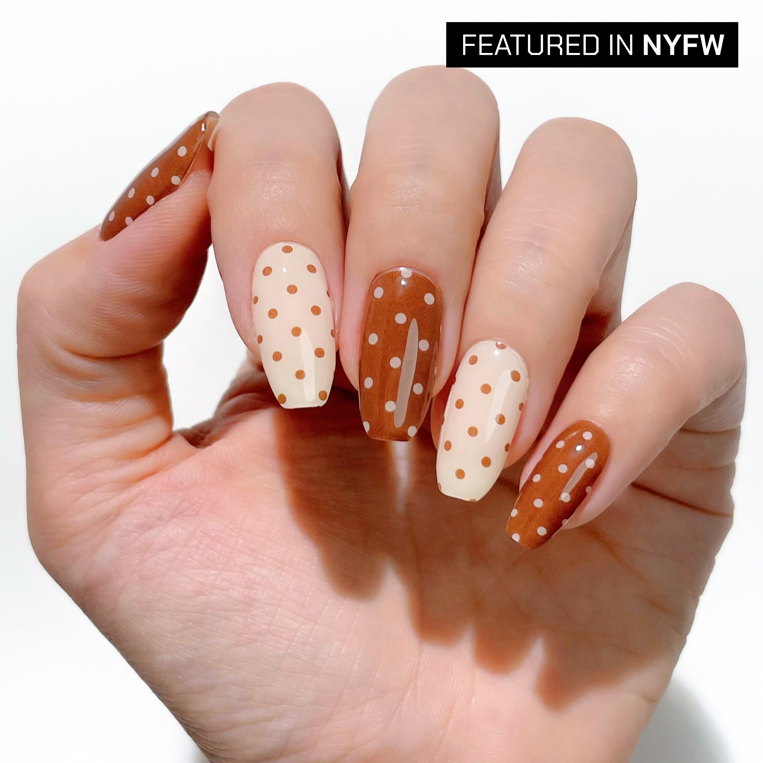 Hand with polka dot nail design on a white background