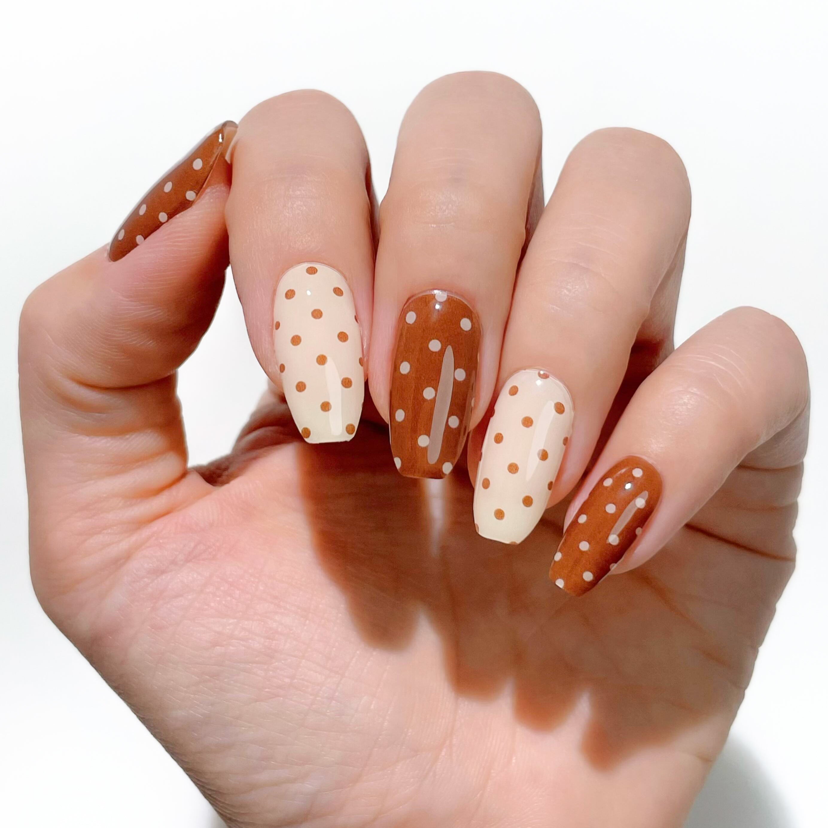 Hand with polka dot nail design on a white background